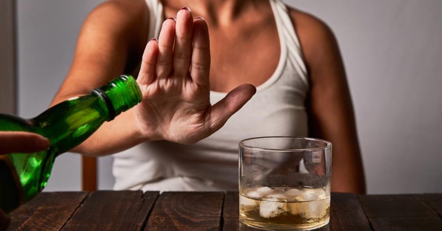 A woman's hand saying don't put any more drink in her glass. Concept of alcoholism and not drinking to drive.