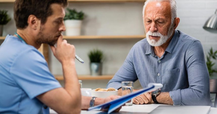 Senior man feeling worried while analzying his medical reports with a doctor during medical appointment.