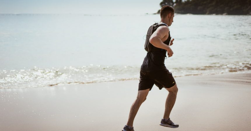 Man running across beach keeping fit